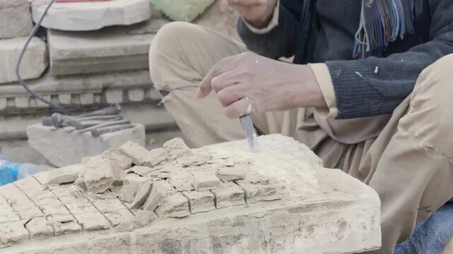 an old man carving the relics of the temple stone for reconstruction of the temple after earthquake.