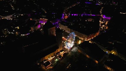 Osnabruck, Germany - December 11, 2025: Aerial view of vibrant Christmas market at night, showcasing colorful lights and festive atmosphere, camera pans across scene