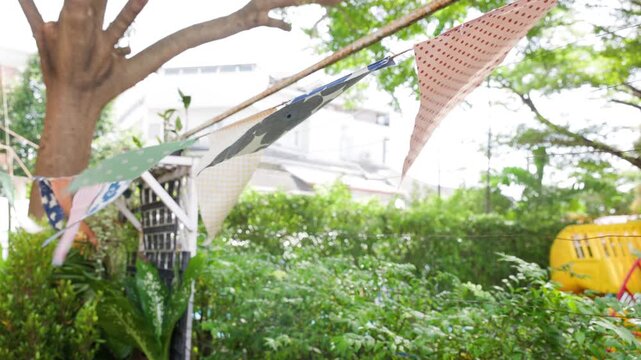 triangle flags is blowing  in garden view background. garland flags among for outdoor party concept.