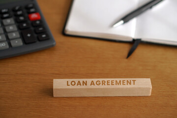 Fototapeta premium LOAN AGREEMENT. Financial and business concepts. Letters on wooden cubes with a calculator and notebook in the background.