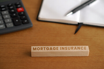 Fototapeta premium Mortgage insurance. Financial and business concepts. Letters on wooden cubes with a calculator and notebook in the background.