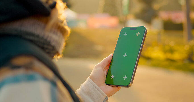 Female holding a smartphone with a green screen for copy space, isolated on green background - Powered by Adobe
