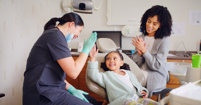Child, high five and dentist for consultation with discussion, oral hygiene and mouth cleaning service. Mother, health professional and orthodontic inspection for dental care with girl for checkup