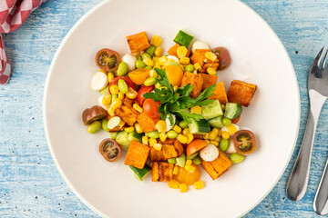 Roasted sweet potato salad mixed with corn, cucumber and herbs