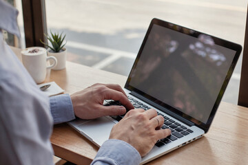 man using laptop computer with blank empty white screen in cafe