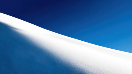 minimalist winter landscape presenting a sweeping white snowdrift curve against a vibrant deep blue sky creating a stark contrast and serene cold natural beauty