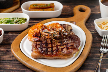 Grilled ribeye steak (beef ribeye) is served with grilled shrimp and side dishes