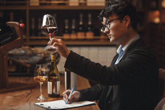 Asian Ethnicity Professional Sommelier Tasting Red Wine in Wine Cellar, Close up Photo. Alcoholic Beverages Degustation. Winemaking School, Wine Waiter Certification.