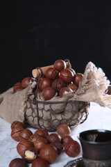 Macadamia nuts in a metal basket on a black background. Natural protein and antioxidant. Dark background.
