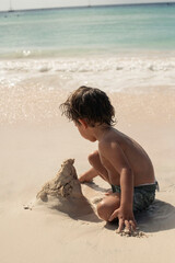 toddler building a castle on white sand beach