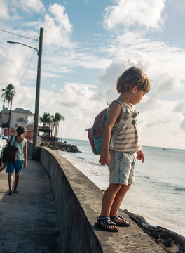 Boy standing on wall in front of ocean