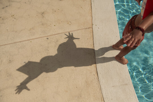 Shadow of young boy jumping into pool on sunny day