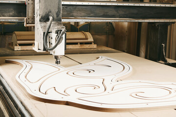 Numerically controlled woodworking machine cuts rounded complex lines on the canvas. Computer numerical control. CNC.