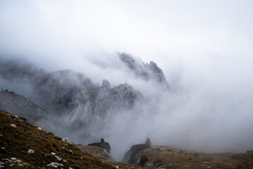 Fog rolling over rugged Dolomites mountains and rocky alpine slopes