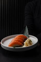 Nigiri with salmon on a white plate on a black background