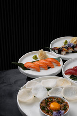 Nigiri with tuna and salmon on a white plate on a black background