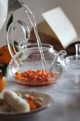 Making sea buckthorn tea in a transparent teapot on a table