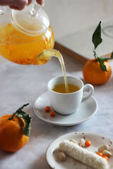 Sea buckthorn tea is poured from a transparent teapot into a cup
