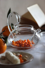Sea buckthorn in a transparent teapot on the table