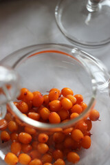 Sea buckthorn in a transparent teapot on the table