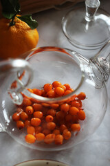 Sea buckthorn in a transparent teapot on the table