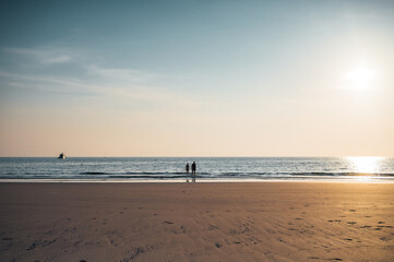 Couple standing in evening surf, Ao Phrao Beach, Koh Kood, Thailand