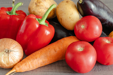 A close-up of farm vegetables. Carrots, onions, bell peppers, and tomatoes are ready for cooking