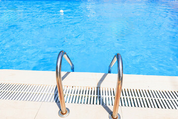 Steps leading into the clear blue water of a swimming pool