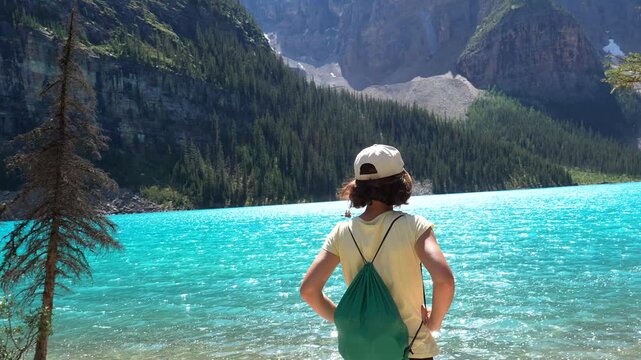 Majestic mountains surround turquoise moraine lake as a tourist contemplates the breathtaking scenery in banff national park, alberta, canada, a unesco world heritage site