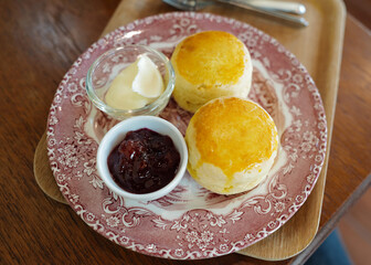 Close up butter scones served with berry jam and clotted cream