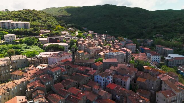 Expansive Aerial Drone Pull Back Shot Panning Out Over Historic Sartene Medieval Town, Revealing Lush Green Mountains and Forest Valley in Southern Corsica, France.