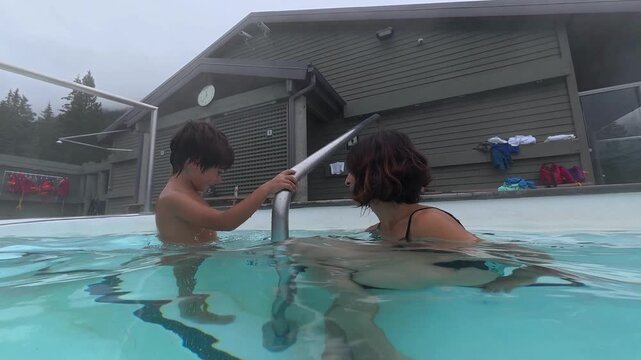 Mother and son are spending quality time together, enjoying the warm, soothing waters of a hot spring in the canadian rockies, surrounded by a serene natural landscape