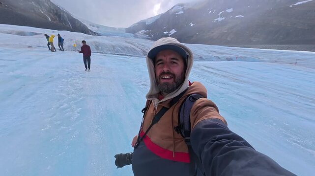 Cheerful traveler wearing casual attire standing near athabasca glacier, showcasing dramatic landscape of columbia icefield within jasper national park's stunning wilderness