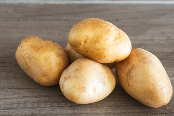 Organic potatoes freshly harvested and arranged on wooden surface showcasing clean unblemished unpeeled skins natural non gmo produce ready for cooking healthy rustic composition