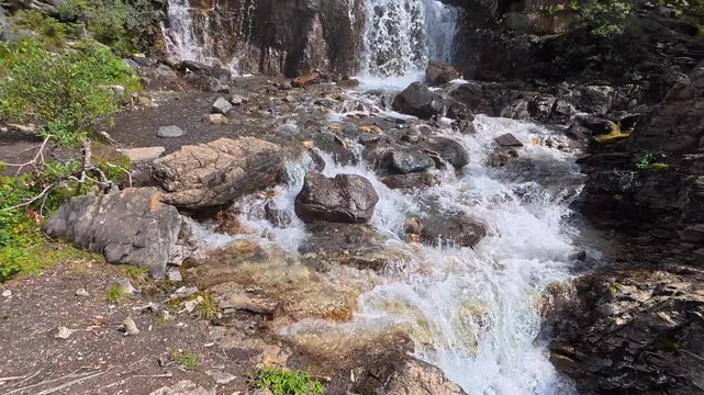 Beautiful tangle creek falls cascading down rocky cliffs, surrounded by lush green forest, as a tourist approaches the edge of the waterfall