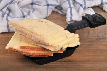 Tranches de fromages vari&eacute;s dans un po&ecirc;lon &agrave; raclette en gros plan