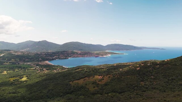 Smooth aerial circling shot over the expansive Gulf of Valinco and Propriano Bay, highlighting the lush green coastline, picturesque town, and dramatic mountains of Southern Corsica, France.