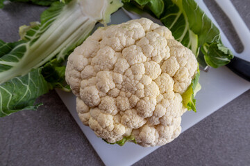 Healthy raw cauliflower vegetable on white board, gray background