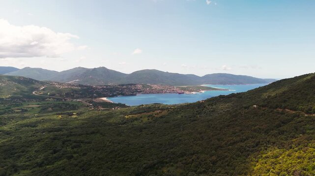 Expansive High Aerial Drone Flyout Over Propriano Bay, Showcasing Charming Coastal Town, Lush Green Landscape, and Dramatic Mountains of Southern Corsica, France.