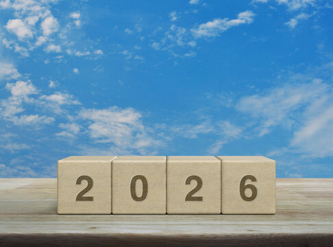 2026 letter on wood block cubes on wooden table over blue sky with white clouds, Happy new year 2026 cover concept