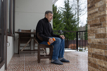 Senior man exercising with dumbbell at home terrace