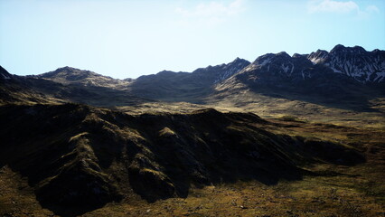 Majestic mountains rise against a brilliant blue sky, illuminated by warm afternoon sunlight. Lush green valleys extend between rocky peaks, showcasing natures beauty and tranquility.