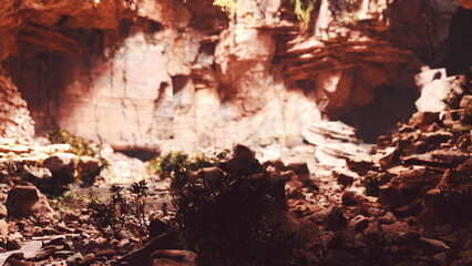A stunning rocky landscape showcases vibrant orange and red hues, contrasting with lush green plants at the base. This scene captures the beauty of nature during the enchanting golden hour.