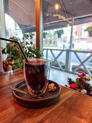 Close-up of mulled wine in a glass cup with cinnamon stick, cloves and orange slices. Traditional hot spiced red wine, cozy winter drink served in a caf&eacute;, perfect for Christmas and holiday atmosphere.