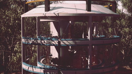 A unique architectural design comes to life amidst greenery. Workers collaborate at various levels, showcasing teamwork and innovation. The structure features circular layers and transparent elements.