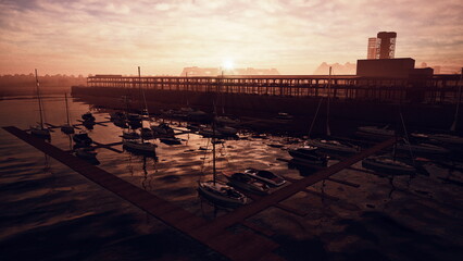 Boats are anchored peacefully in a marina as the sun sets behind the horizon. Warm hues reflect on the waters surface, creating a serene evening atmosphere by the docks. © icetray