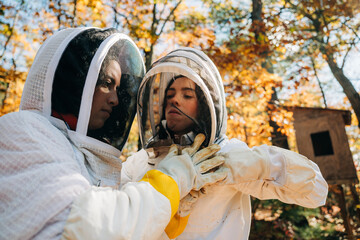 Beekeeper adjusts partner's veil in forest with fall colors