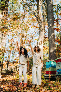 Women beekeepers reaching for bees in autumn forest