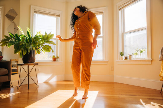 Woman dancing freely in sunny living room