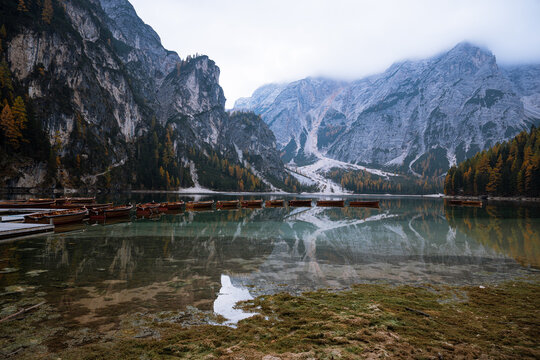 Wooden boats at Lago di Braies with alpine mountains in autumn
